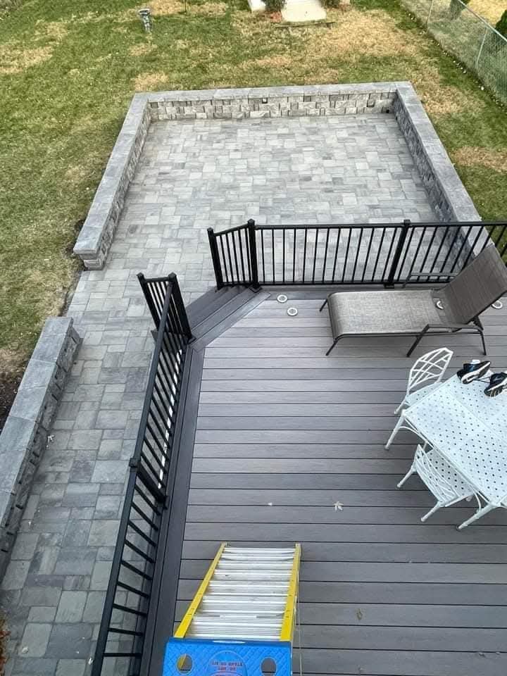 Aerial view of a grey paver patio with seat walls below a new deck